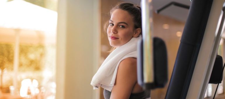 Young woman exercising in a gym with a towel around her neck, exuding health and fitness.